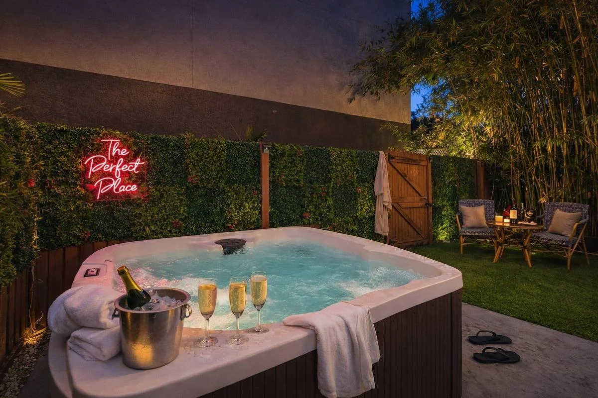 Private hot tub with red neon The Perfect Place sign, champagne bucket and bamboo garden at St. Pete bungalow