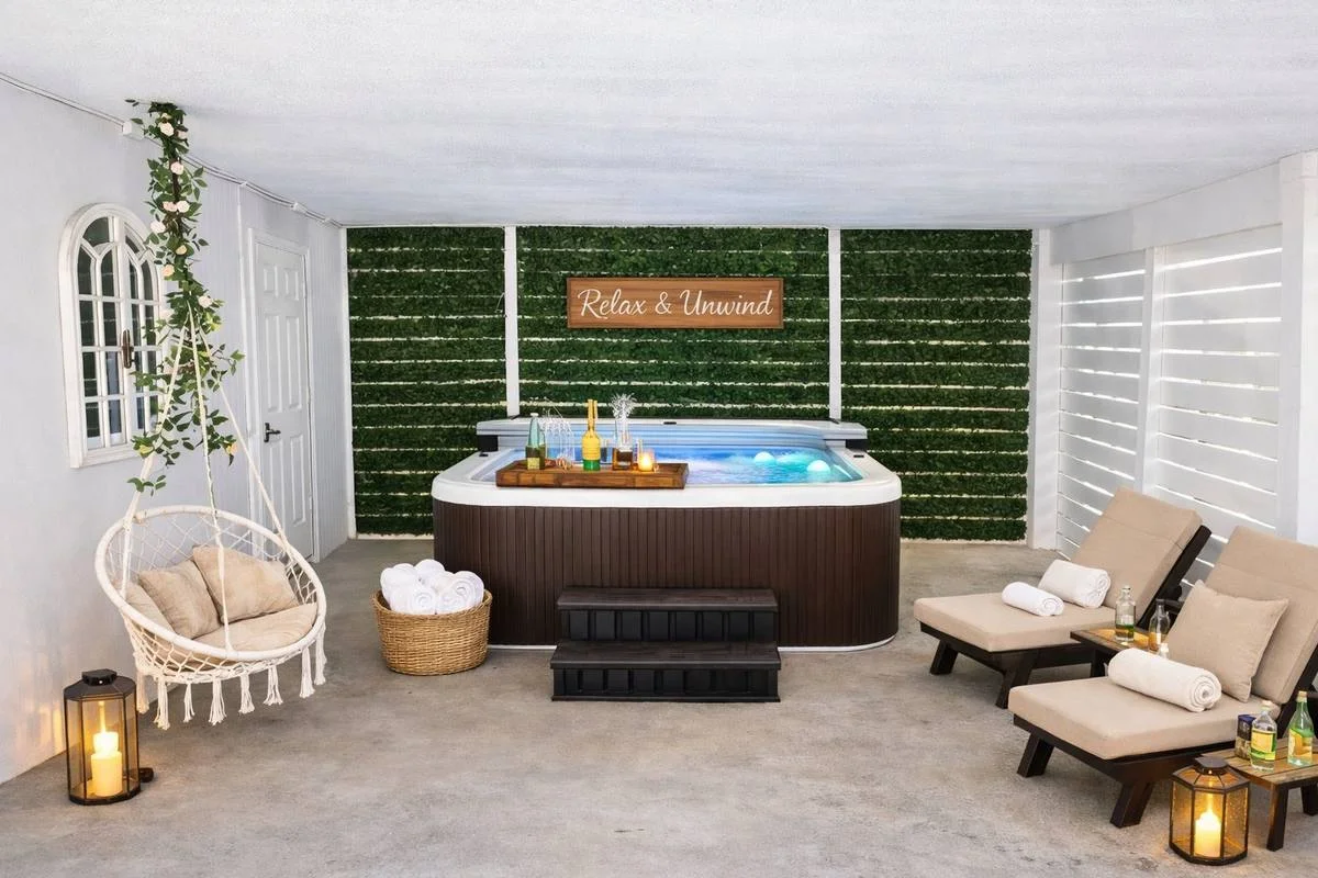Private hot tub with Relax and Unwind neon sign, hanging swing chair and lounge chairs at Indian Rocks Beach rental